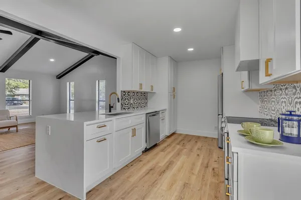 a kitchen with a sink a stove cabinets and wooden floor