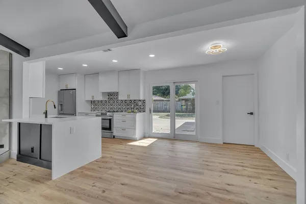 a large kitchen with stainless steel appliances granite countertop a large counter top and a wooden floors