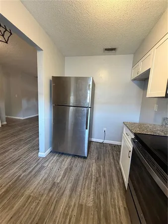 a kitchen with a refrigerator a stove and wooden floor