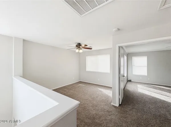 an empty room with windows and fan