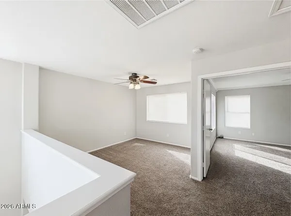 an empty room with windows and fan