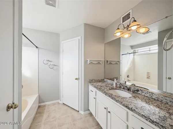 a bathroom with a granite countertop sink a mirror and a shower