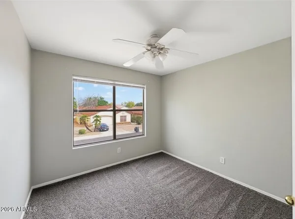 an empty room with a window and a fan
