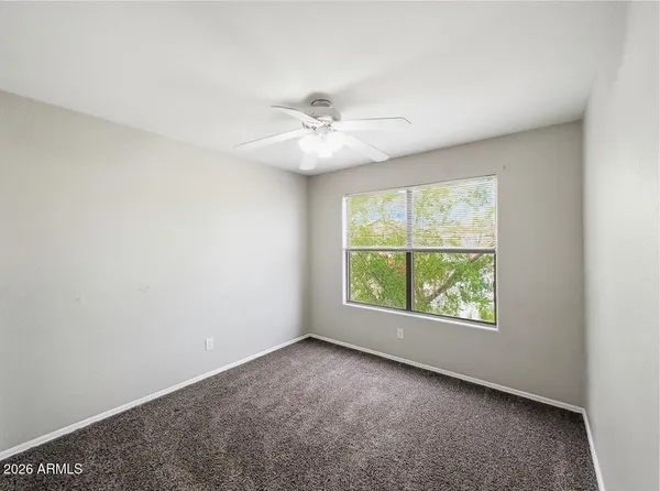 an empty room with a window and a fan