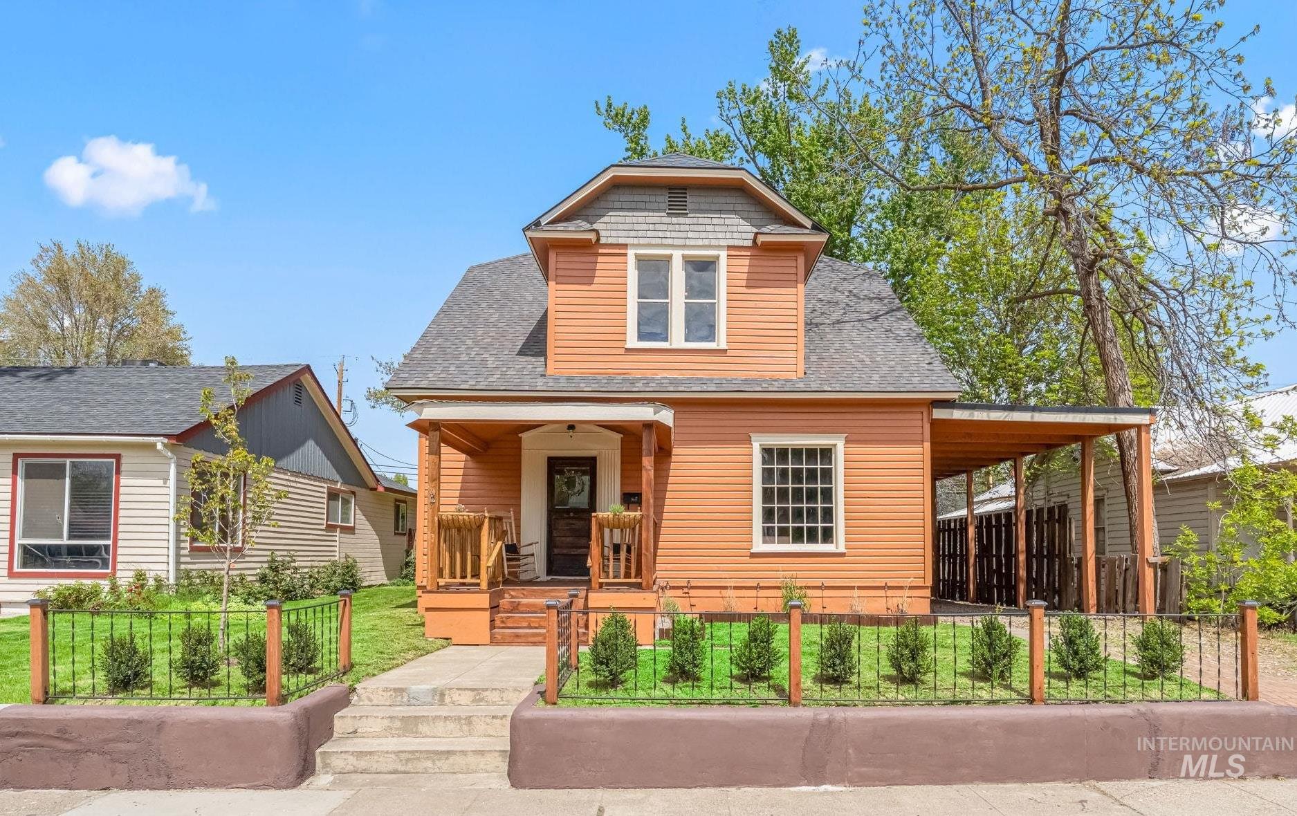 Two-story home with terracotta siding, a covered front porch, and an extended side carport