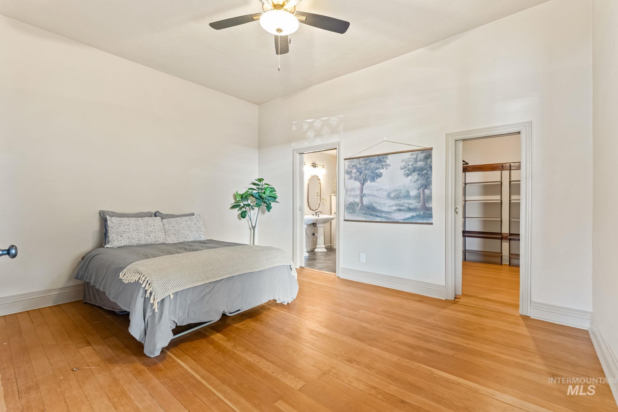 424 West Main Street Weiser, ID 83672 - Photo 13 of 30 Main level primary bedroom. Spacious room featuring wood-finish flooring, a ceiling fan, and white baseboard molding