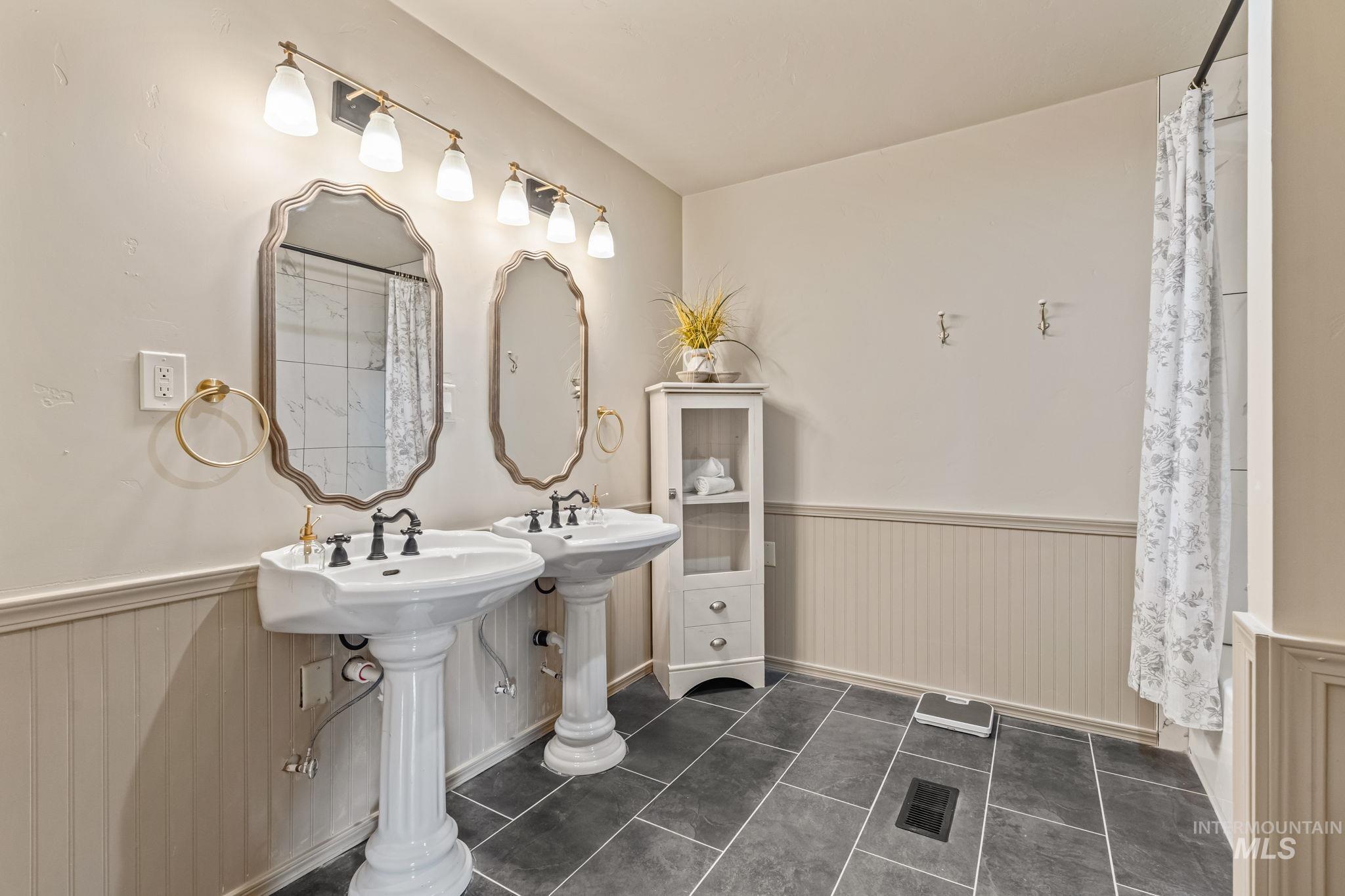 424 West Main Street Weiser, ID 83672 - Photo 15 of 30 Bathroom featuring dual pedestal sinks with black fixtures, framed mirrors, and wall-mounted light fixtures