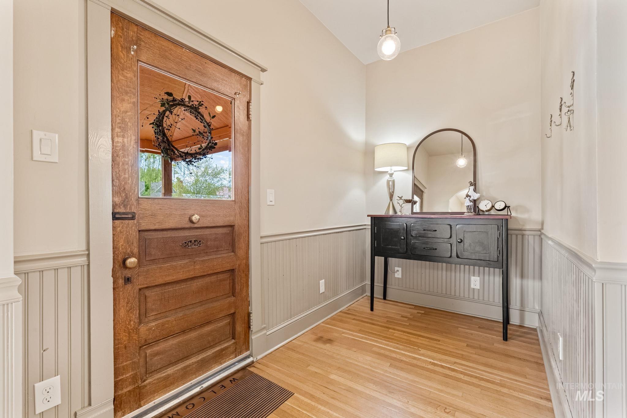 424 West Main Street Weiser, ID 83672 - Photo 2 of 30 Entryway featuring a paneled wood door with glass insert, wood-finish flooring, beadboard wainscoting, and a ceiling-mounted pendant light