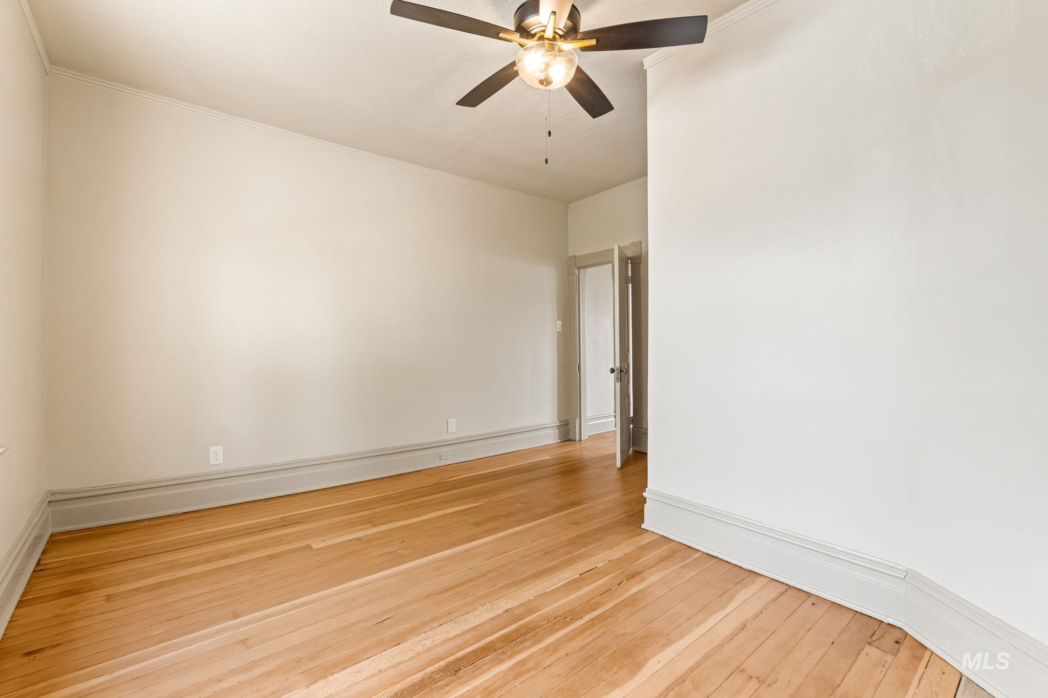 424 West Main Street Weiser, ID 83672 - Photo 21 of 30 Room featuring wood-finish flooring, light-toned walls, a ceiling fan with integrated lighting, and crown molding