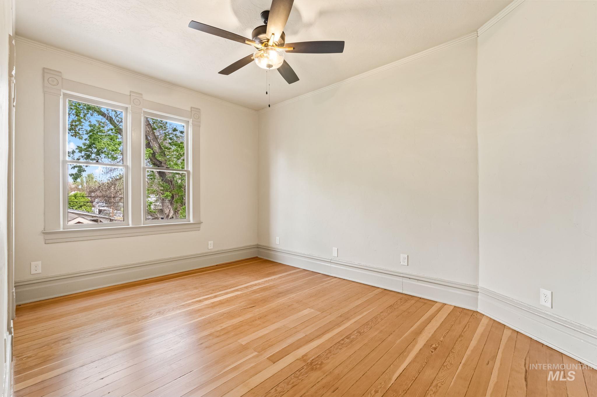 424 West Main Street Weiser, ID 83672 - Photo 22 of 30 Bright interior space featuring wood-finish flooring, a ceiling fan with integrated lighting, and a large window with decorative trim