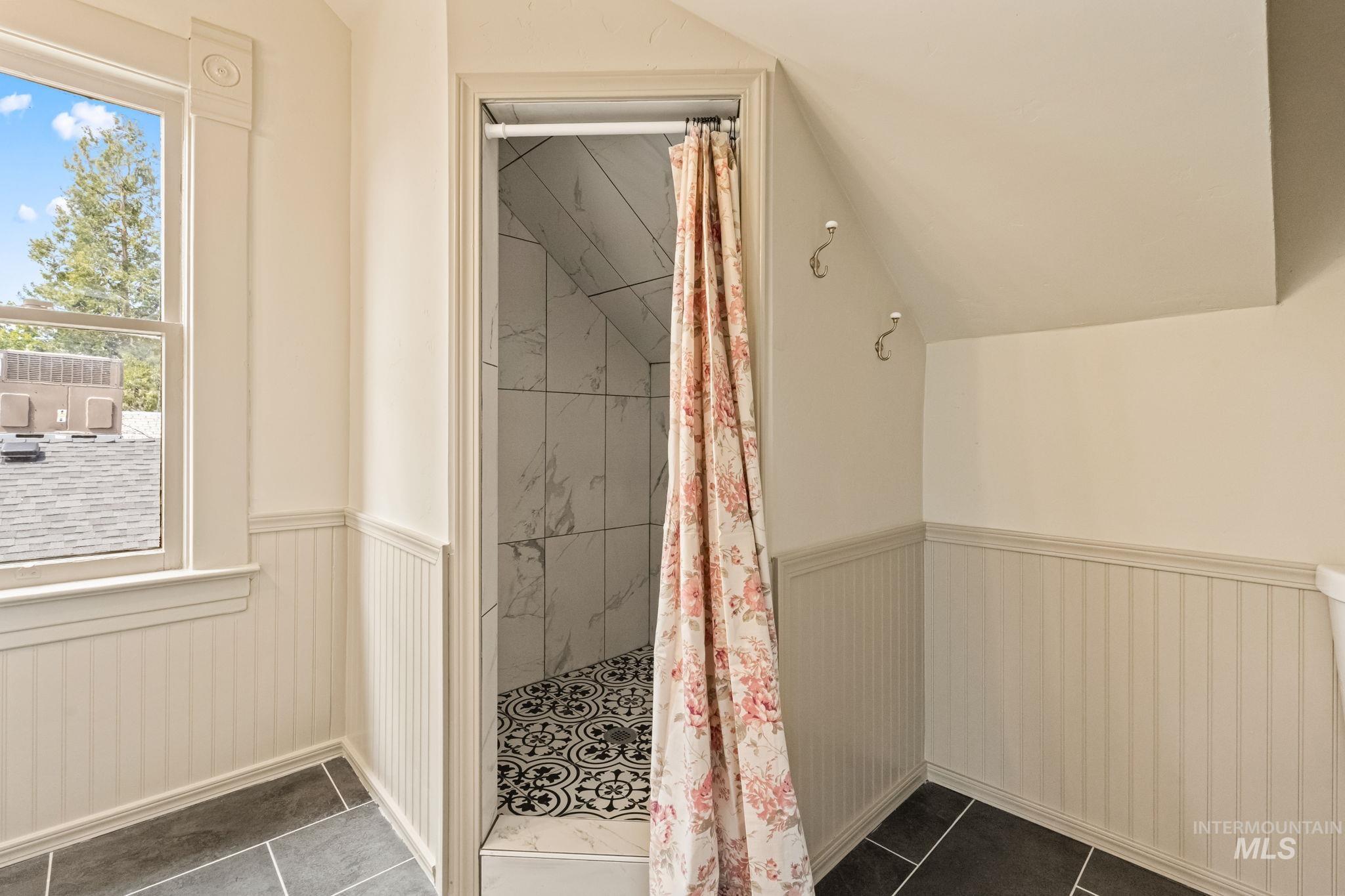 424 West Main Street Weiser, ID 83672 - Photo 24 of 30 Tiled shower with decorative floor, white marble-look wall tiling, and sloped ceiling