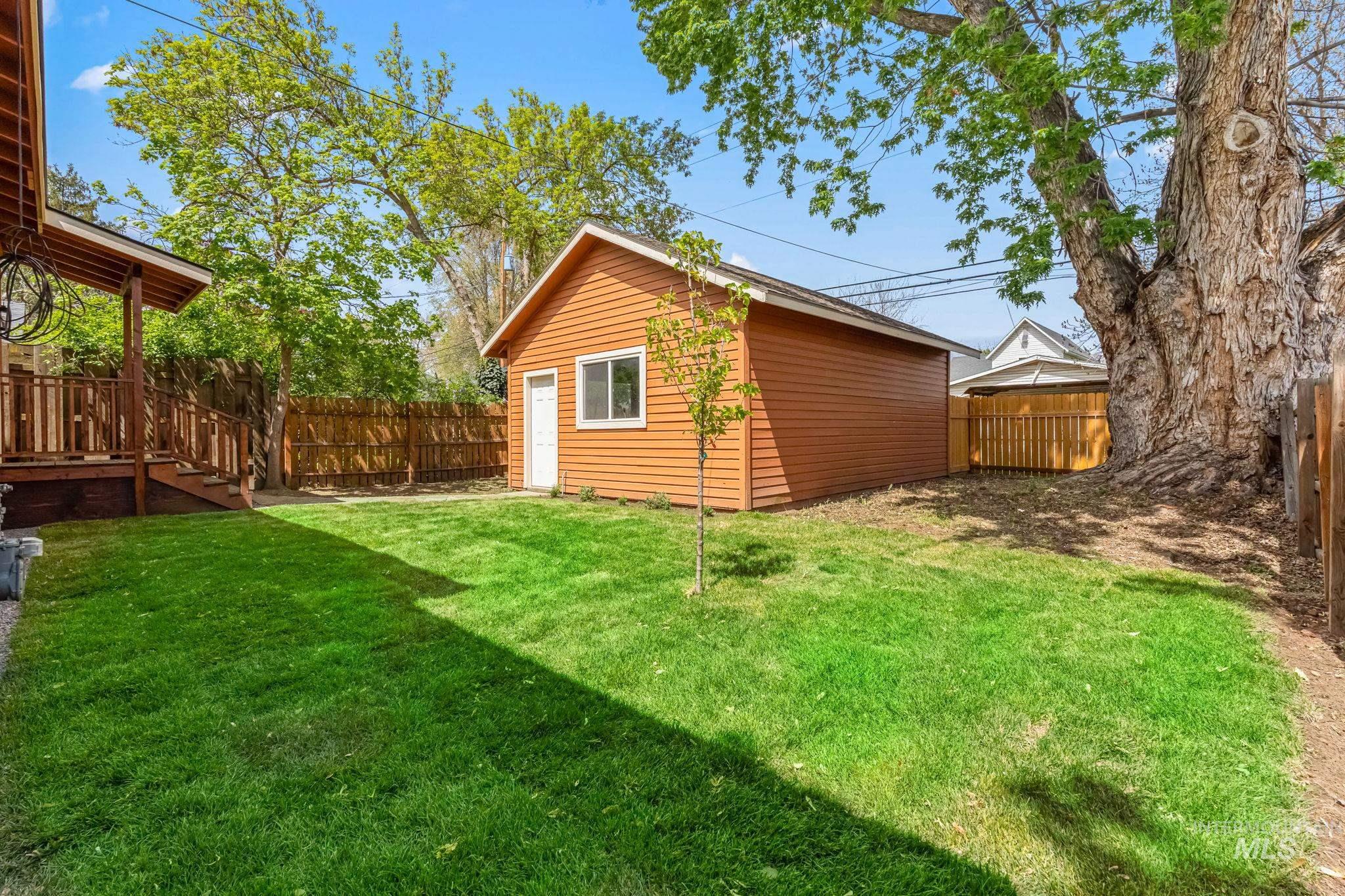 424 West Main Street Weiser, ID 83672 - Photo 28 of 30 Expansive lawn featuring a detached accessory building, wood privacy fencing, and a covered porch with wood railing