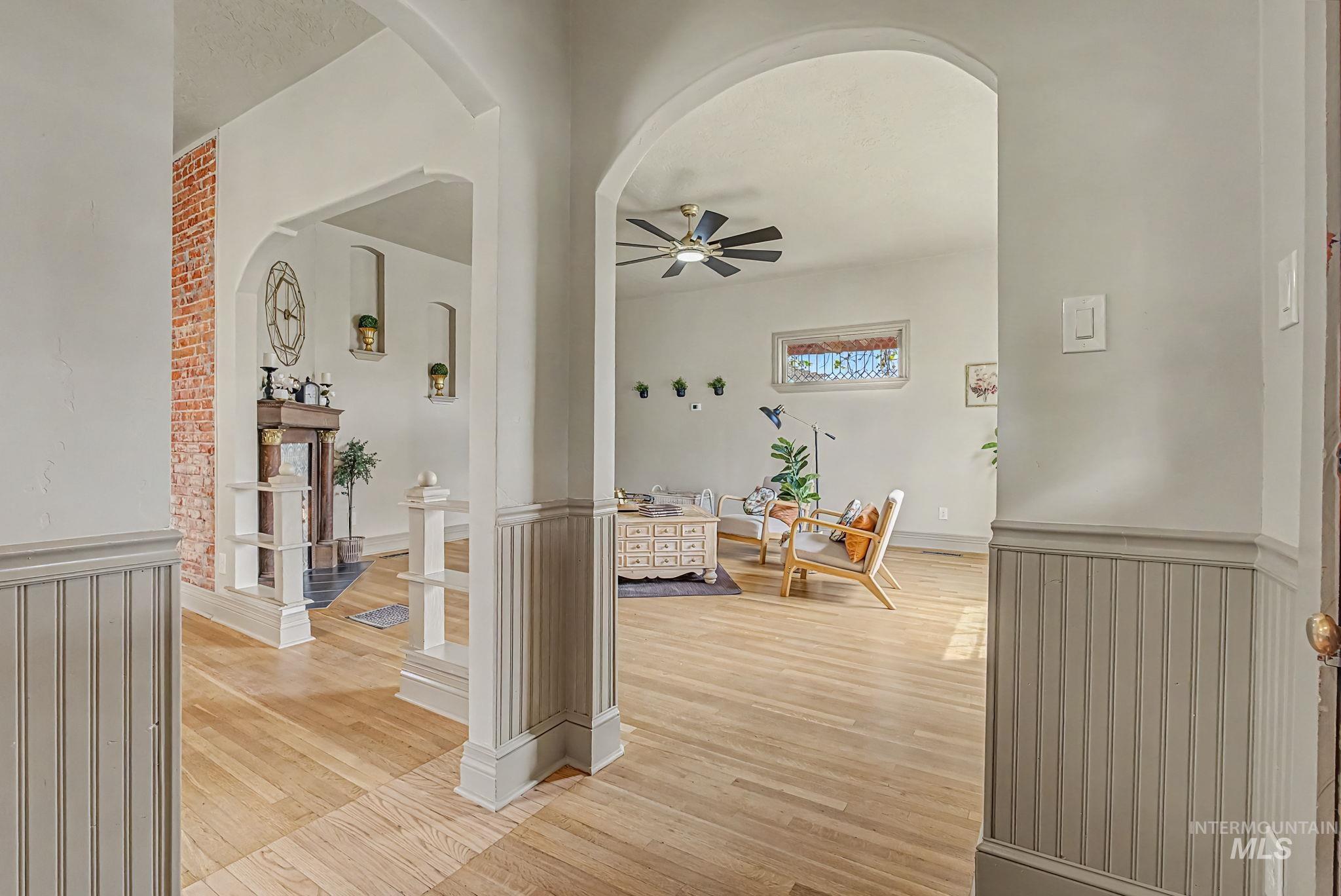 424 West Main Street Weiser, ID 83672 - Photo 3 of 30 Archways framing the entry into a living space, featuring wood-finish flooring, wainscoting details, and a visible brick accent wall
