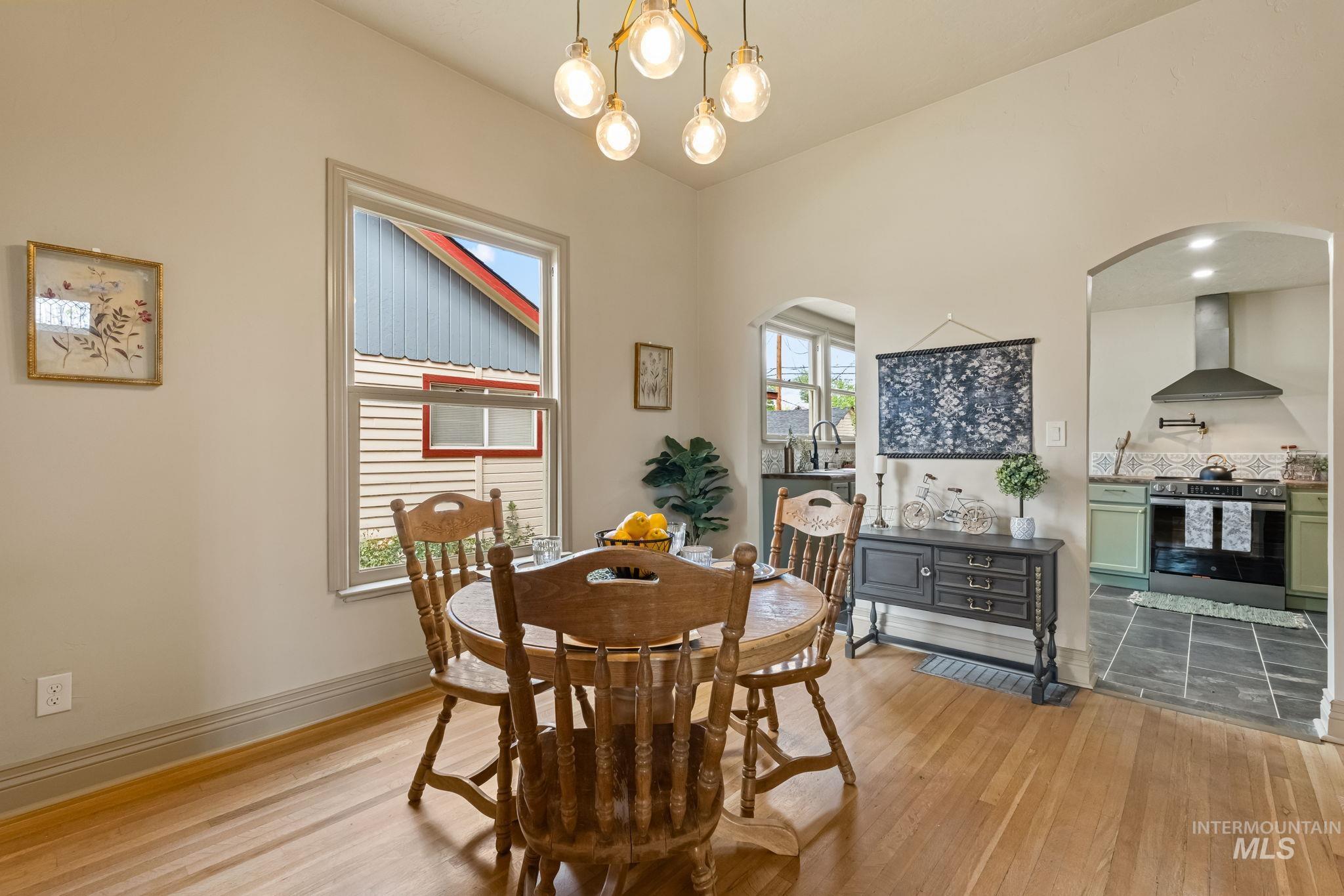 424 West Main Street Weiser, ID 83672 - Photo 5 of 30 Bright dining space featuring wood-finish flooring, a contemporary chandelier, and an arched doorway opening to the kitchen