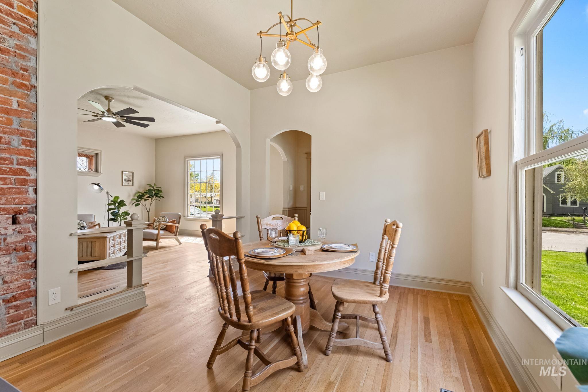 424 West Main Street Weiser, ID 83672 - Photo 6 of 30 Hardwood flooring throughout, arched doorways, exposed brick wall, a multi-globe chandelier, and a large window with exterior visibility