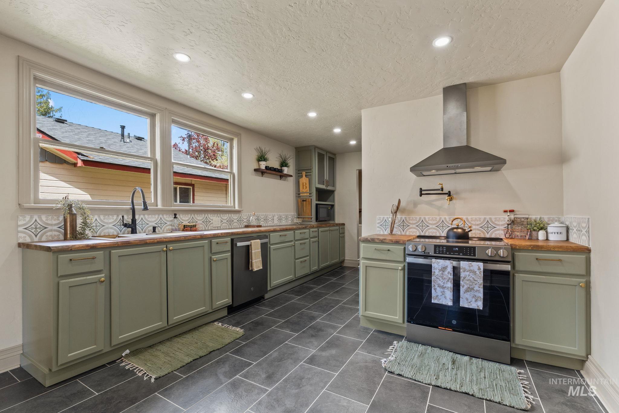 424 West Main Street Weiser, ID 83672 - Photo 7 of 30 Kitchen featuring sage green cabinetry, wood-finish countertops, and dark gray tile flooring