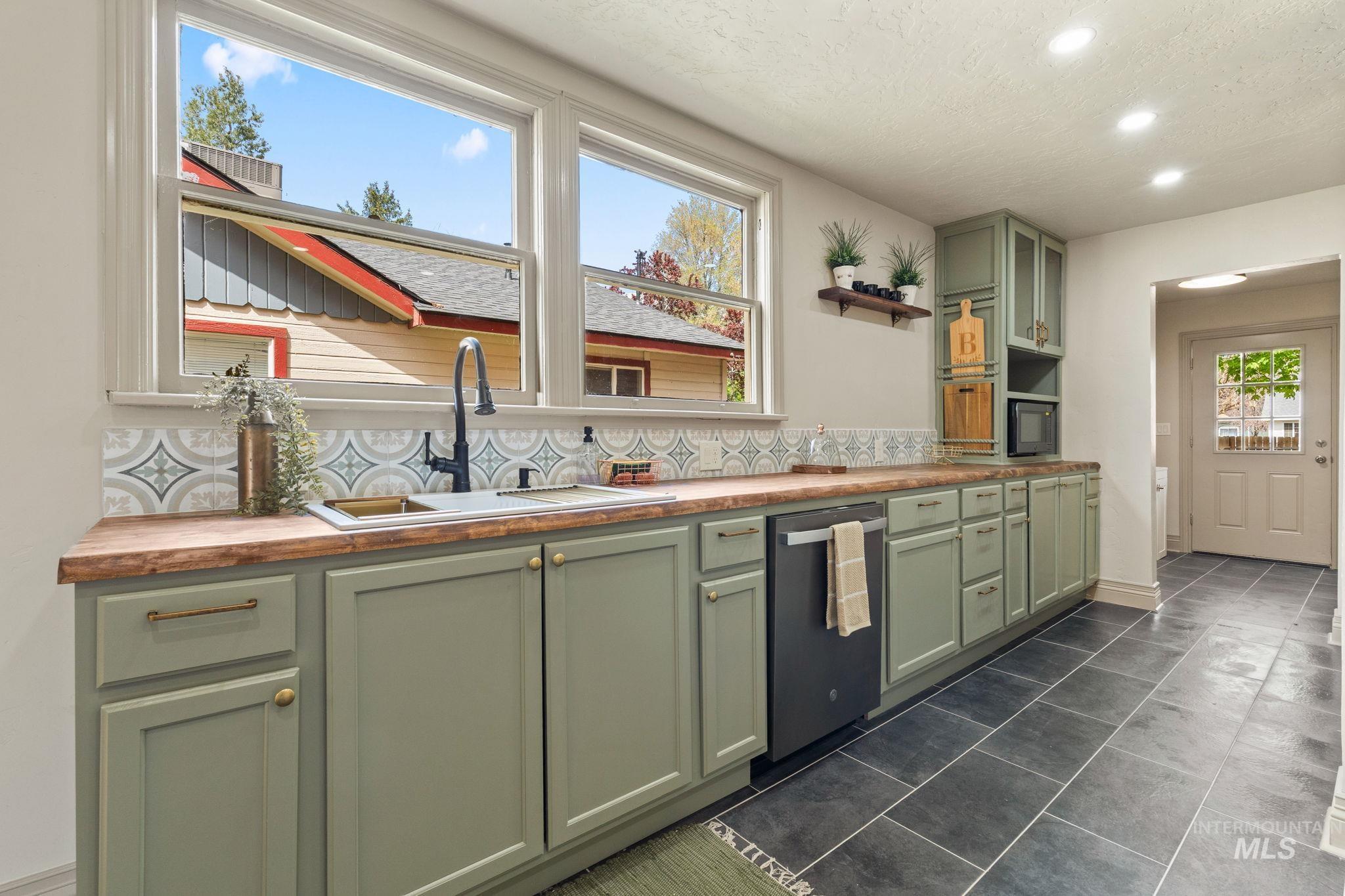 424 West Main Street Weiser, ID 83672 - Photo 9 of 30 Kitchen featuring sage green cabinetry with brass hardware, wood-finish countertops, and a patterned tile backsplash