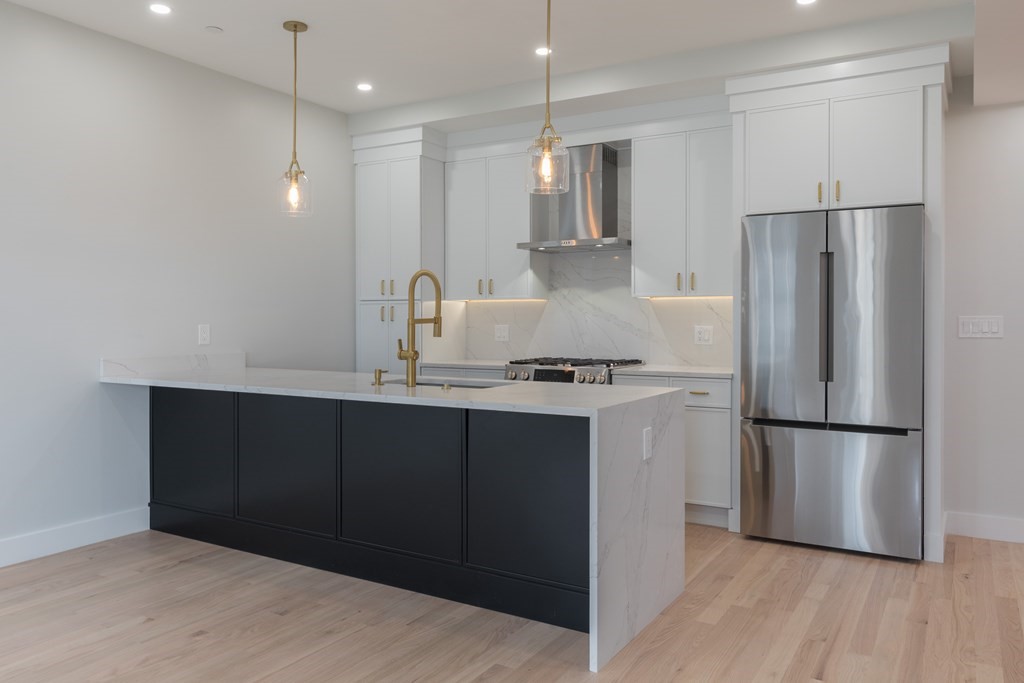 218 Brooks Street, Unit 2 Boston, MA 02128 - Photo 1 of 1 a kitchen with kitchen island a counter top space wooden floor and refrigerator