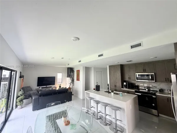 a living room with stainless steel appliances kitchen island furniture and a flat screen tv