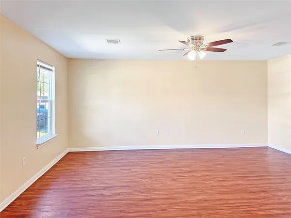 a view of an empty room with wooden floor and a window
