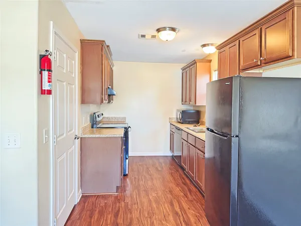 a kitchen with granite countertop a refrigerator stove top oven and sink