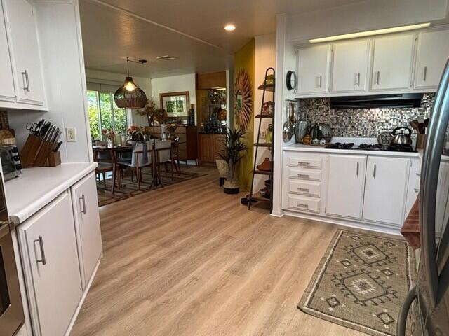 49305 Highway 74, Unit 109 Palm Desert, CA 92260 - Photo 6 of 52 a kitchen with stainless steel appliances kitchen island granite countertop a refrigerator a stove a sink and white cabinets with wooden floor