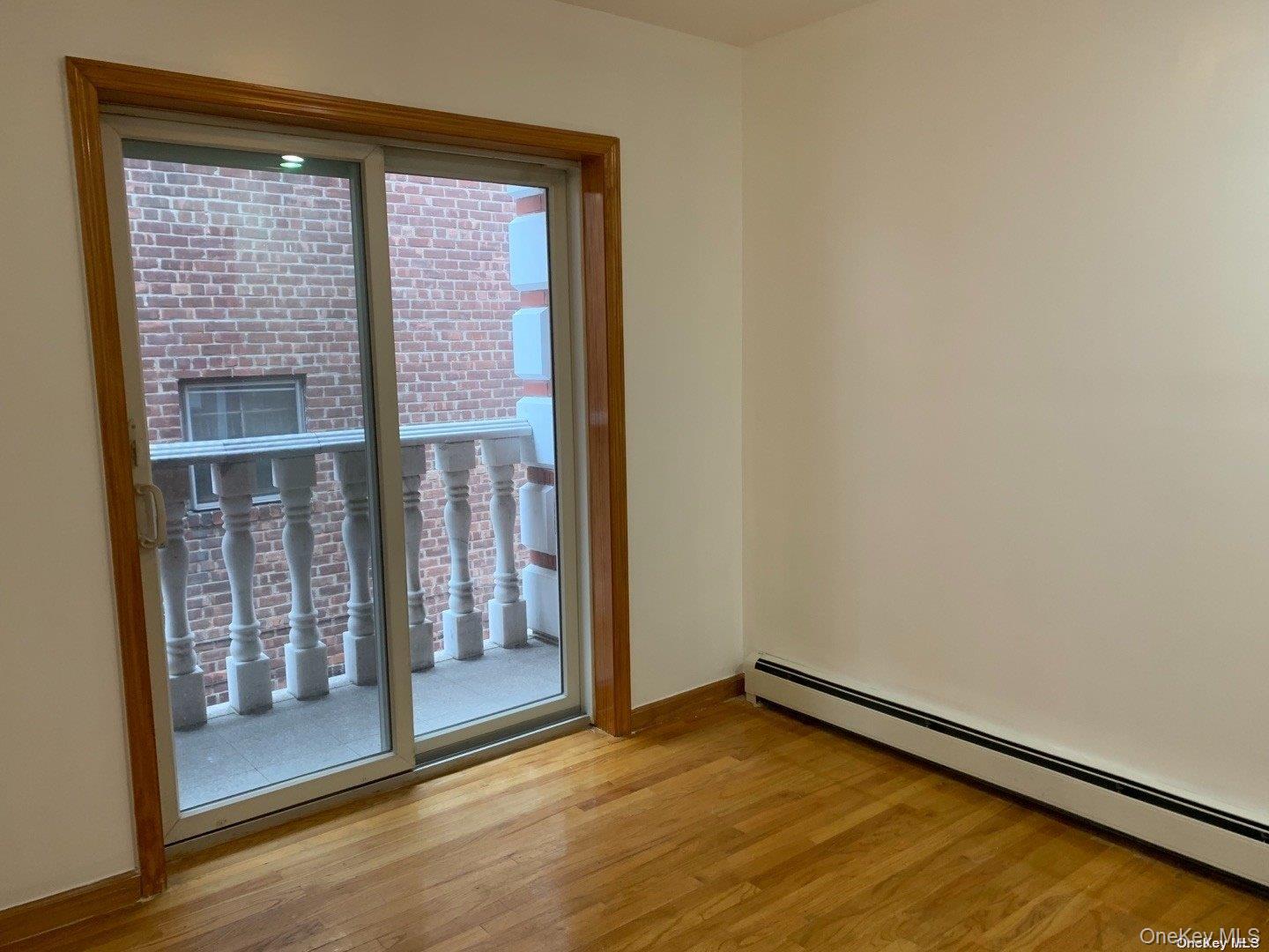 142-05 45th Avenue Queens, NY 11355 - Photo 4 of 9 Spare room with light wood-style flooring, baseboards, and a baseboard heating unit
