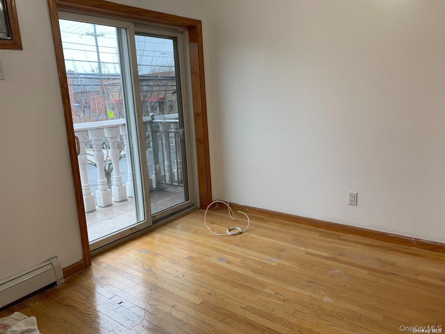 142-05 45th Avenue Queens, NY 11355 - Photo 6 of 9 Unfurnished room featuring baseboards, a baseboard heating unit, and hardwood / wood-style flooring