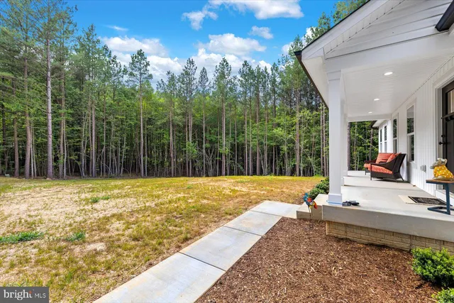 a view of swimming pool with lawn chairs and large trees