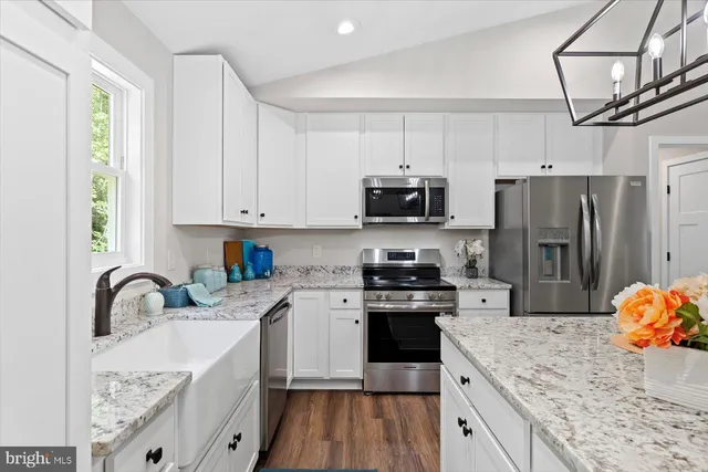 a kitchen with stainless steel appliances a sink a stove a refrigerator cabinets and a window