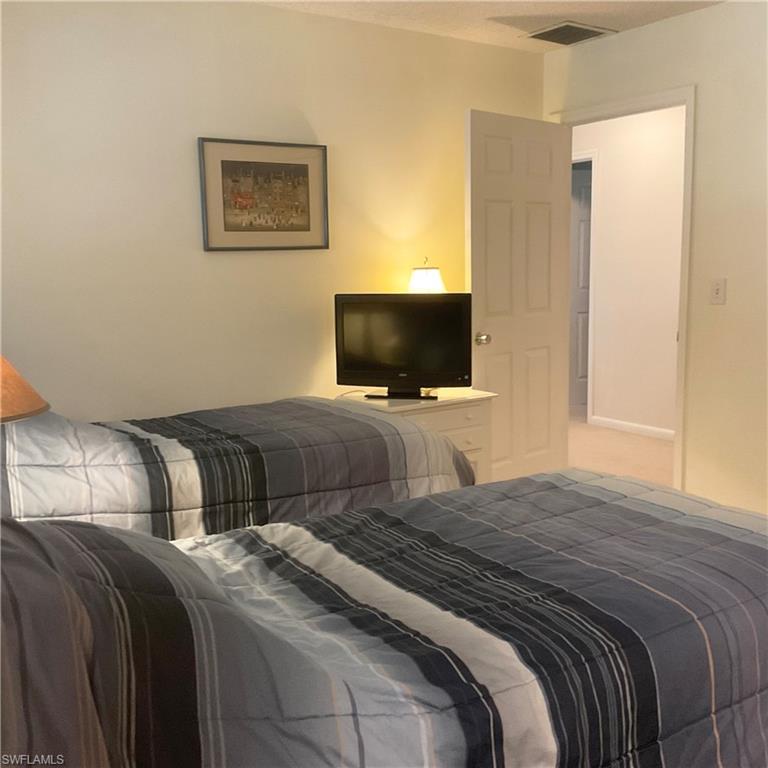 1165 Clam Court, Unit 7 Naples, FL 34102 - Photo 26 of 34 a bedroom with a bed and a flat screen tv