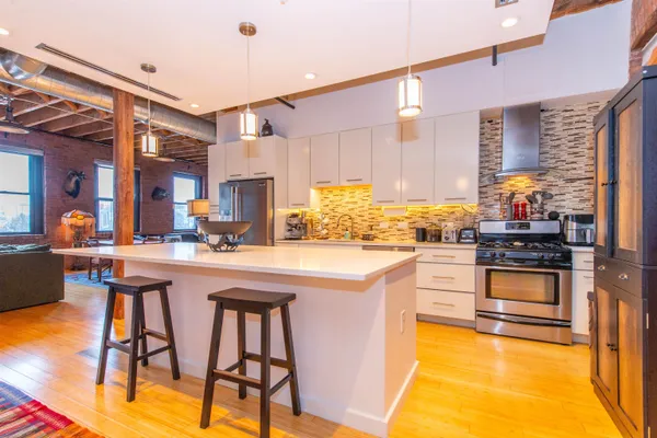 a kitchen with stainless steel appliances granite countertop a stove a sink dishwasher and a refrigerator with wooden floor