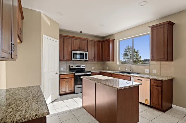 a kitchen with stainless steel appliances granite countertop a stove top oven a sink dishwasher and a refrigerator