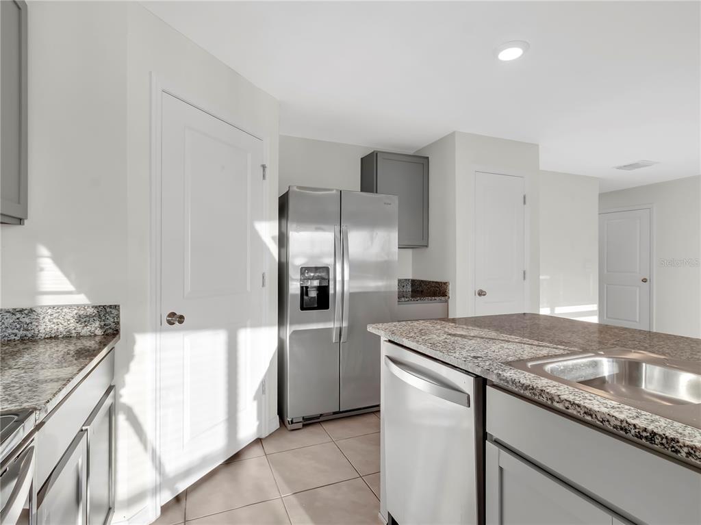 16645 Mosaic Oar Drive Wimauma, FL 33598 - Photo 11 of 43 a kitchen with granite countertop a sink and refrigerator