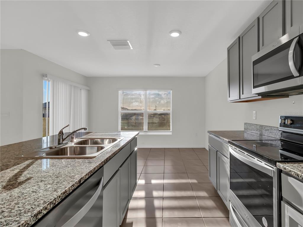 16645 Mosaic Oar Drive Wimauma, FL 33598 - Photo 13 of 43 a kitchen with granite countertop a sink and a stove