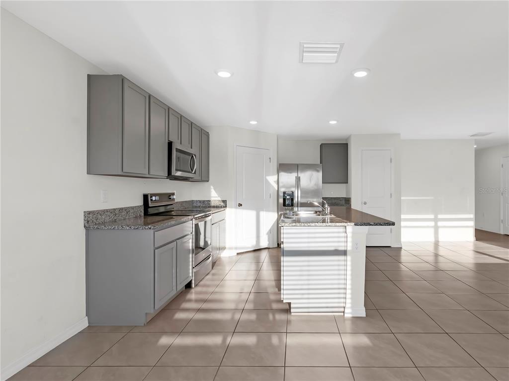 16645 Mosaic Oar Drive Wimauma, FL 33598 - Photo 9 of 43 a kitchen with stainless steel appliances granite countertop a stove top oven a sink a counter top space and cabinets