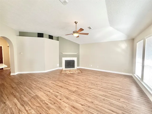 a view of an empty room with window and wooden floor