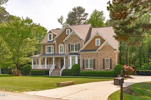 a front view of a house with a garden and trees