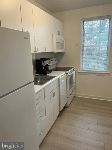 a kitchen with stainless steel appliances white cabinets and wooden floors