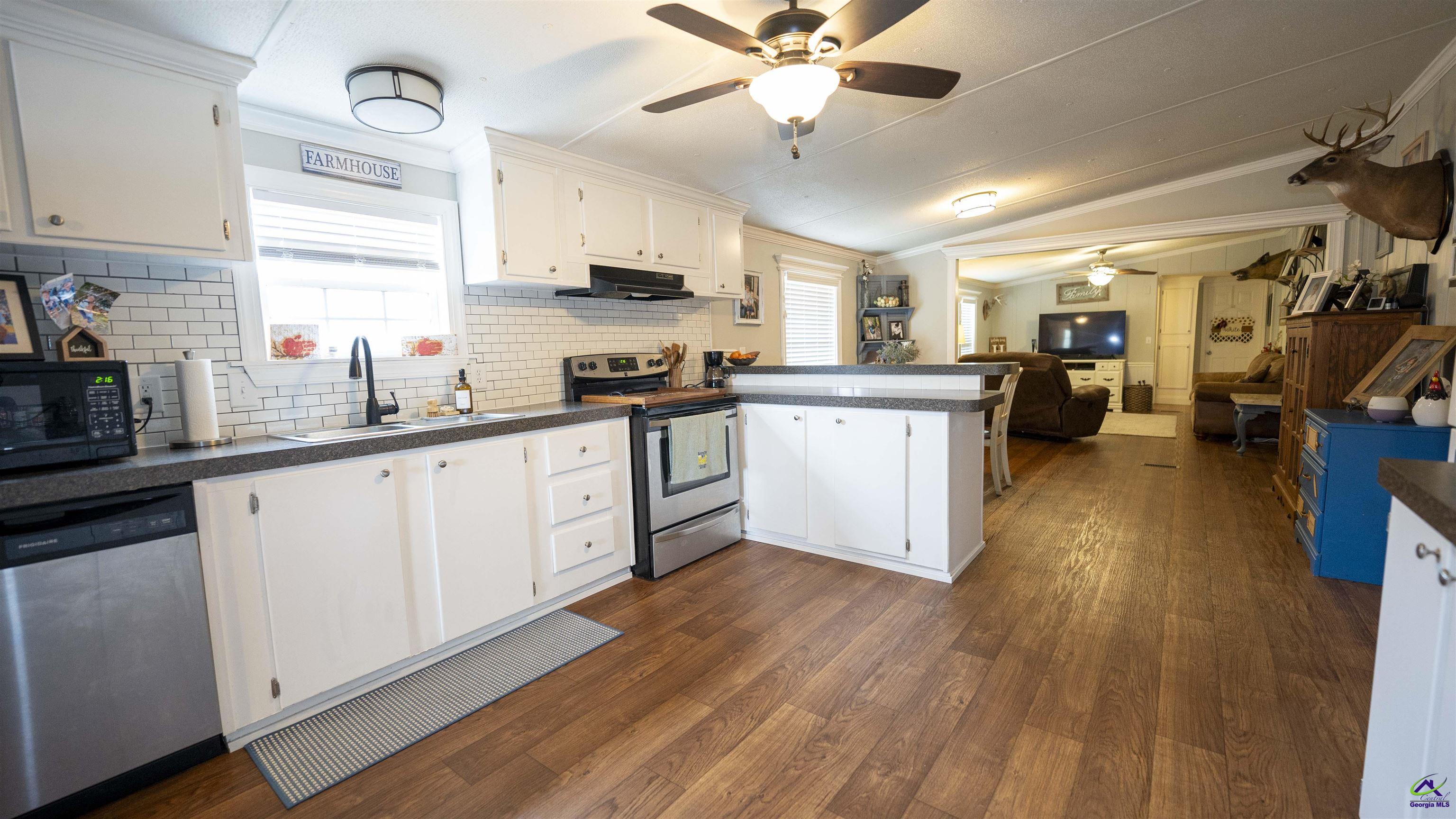 500 Old Milledgeville Road Cochran, GA 31014 - Photo 34 of 48 a kitchen with stainless steel appliances granite countertop wooden floors and white cabinets