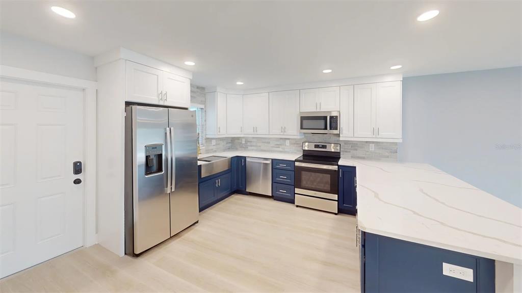 500 129th Avenue East, Unit 2 Madeira Beach, FL 33708 - Photo 5 of 16 a kitchen with granite countertop a refrigerator and a stove top oven