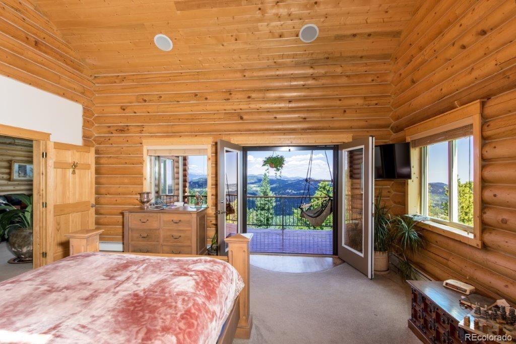 8044 Rossman Gulch Road Morrison, CO 80465 - Photo 23 of 34 a spacious bedroom with a bed and glass door