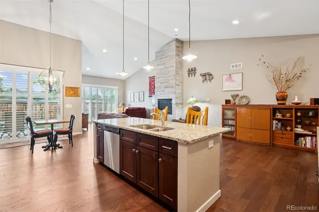 a kitchen with stainless steel appliances granite countertop a sink a stove and a dining table with wooden floor
