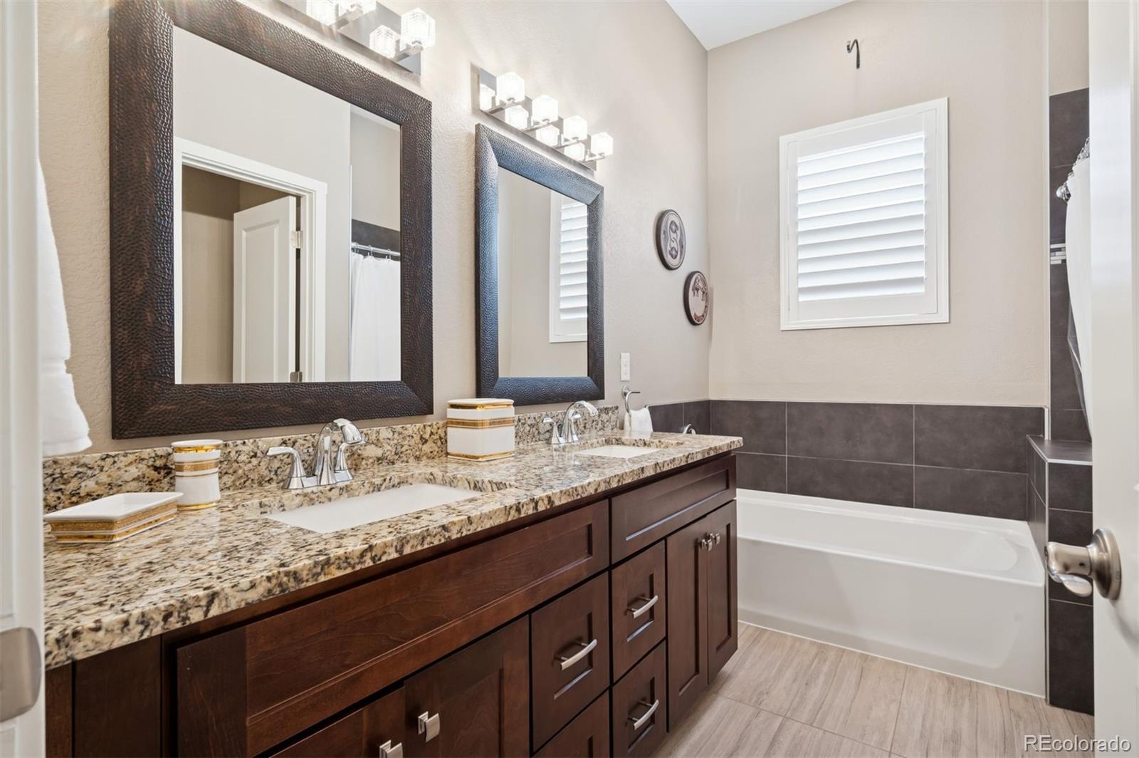 5795 Xenon Way Arvada, CO 80002 - Photo 20 of 33 a bathroom with a granite countertop bathtub a double vanity sink and a mirror