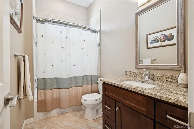 a bathroom with a granite countertop sink toilet a mirror and shower