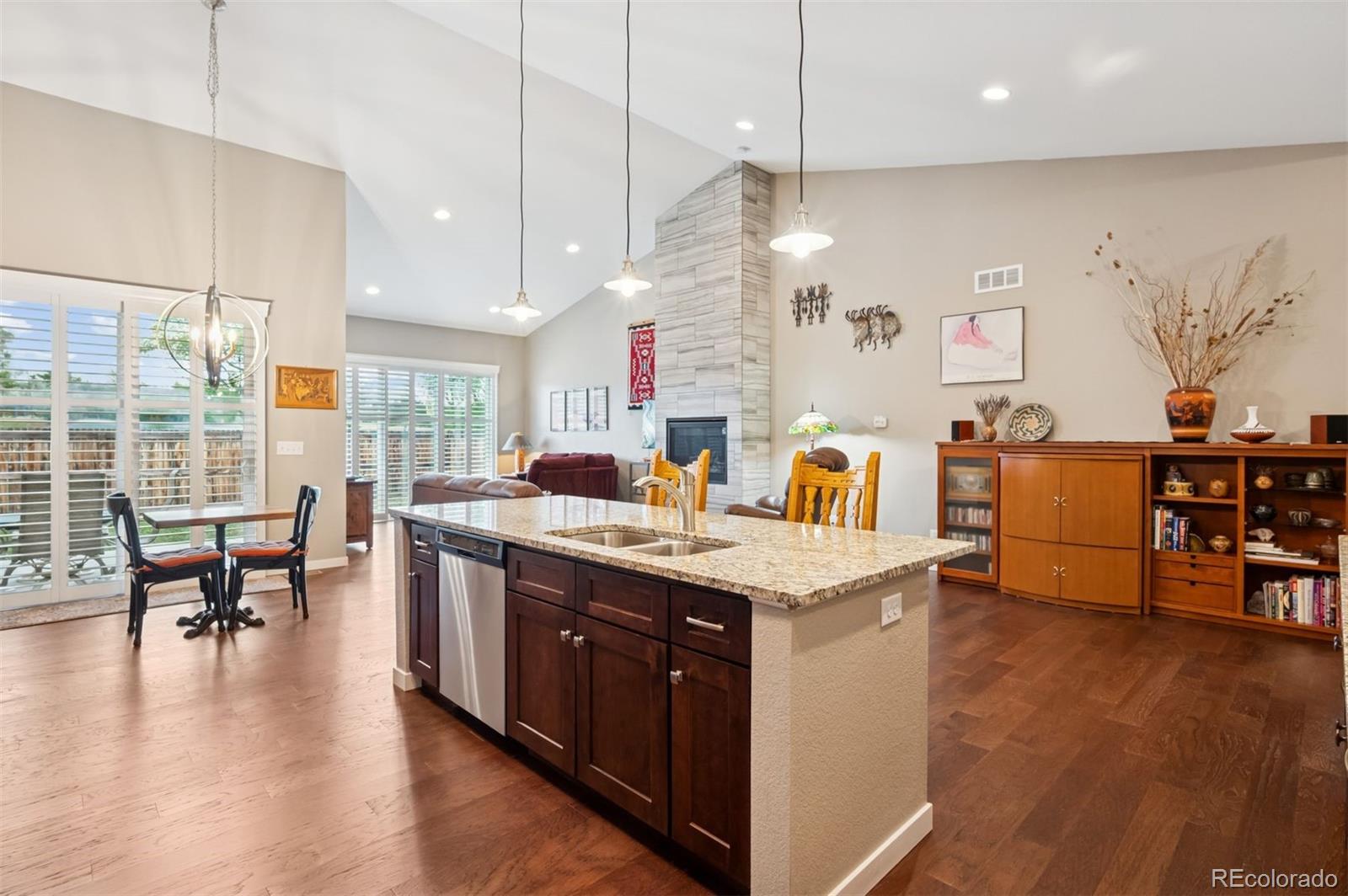 5795 Xenon Way Arvada, CO 80002 - Photo 4 of 33 a kitchen with stainless steel appliances granite countertop a sink a stove and a dining table with wooden floor
