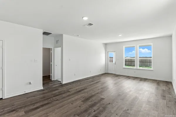a view of an empty room with wooden floor and windows