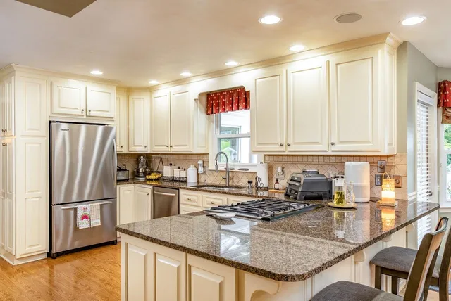 a kitchen with stainless steel appliances granite countertop a sink refrigerator and cabinets