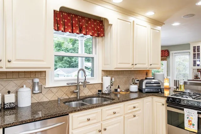 a kitchen with granite countertop a sink stainless steel appliances and cabinets