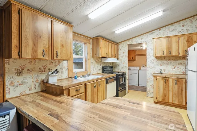 a kitchen with stainless steel appliances granite countertop a refrigerator a stove and a sink with wooden floor